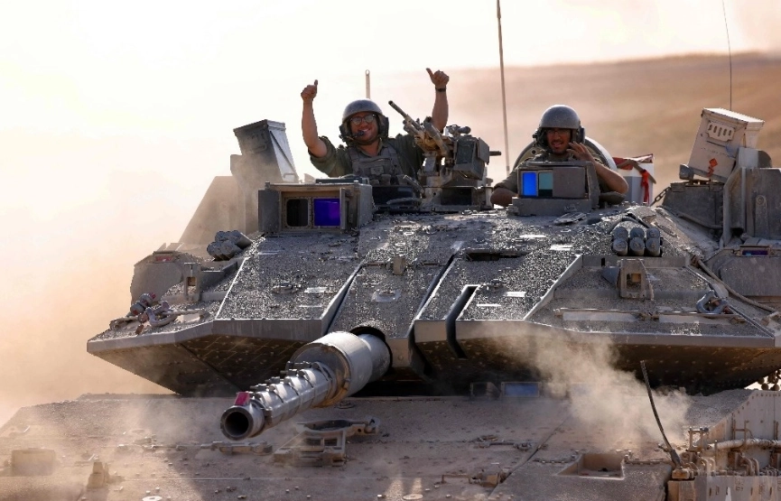 Soldados israelíes hacen un gesto desde un vehículo militar en el sur de Israel, cerca de la frontera con la Franja de Gaza.