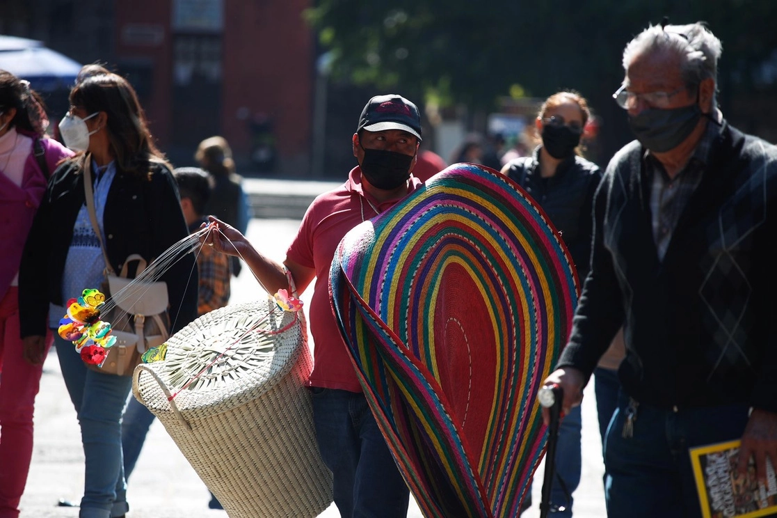 La proporción de personas ocupadas en la informalidad se mantiene casi igual, y representan 56 por ciento de la fuerza laboral del país. En la imagen, un vendedor ambulante exhibe su mercancía en el centro de la alcaldía Coyoacán, el 9 de enero de 2022. Foto Cristina Rodríguez



