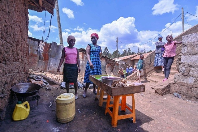 Una estudiante trabaja con su mamá en un barrio pobre de Nairobi, mientras las escuelas permanecen cerradas. Foto Afp