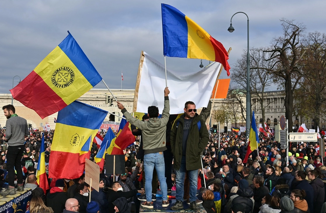 Manifestantes ondean banderas del partido ultraderechista rumano Alianza para la Unión de los Rumanos, durante un mitin convocado por el Partido de la Libertad (extrema derecha) de Austria, contra las medidas oficiales para frenar una nueva expansión del Covid-19. La protesta ocurrió en la plaza Maria Theresien de Viena, el 20 de noviembre de 2021. Foto Afp