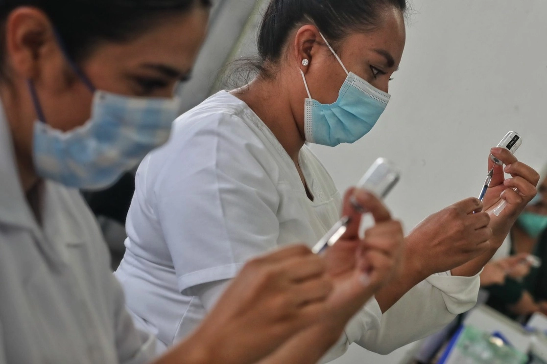Personal médico prepara las dosis de la vacuna de AstraZeneca para inocular a jóvenes de 18 a 29 años en el Palacio de los Deportes, en la Ciudad de México, el 20 de octubre de 2021. Foto Marco Peláez 