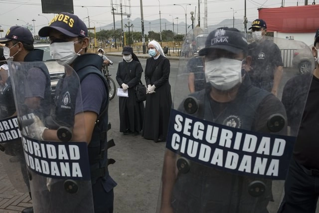 Policías peruanos vigilan los alrededores de la Plaza de Toros de Acho, en Lima, mientras monjas dan de comer a indigentes. Foto Ap 