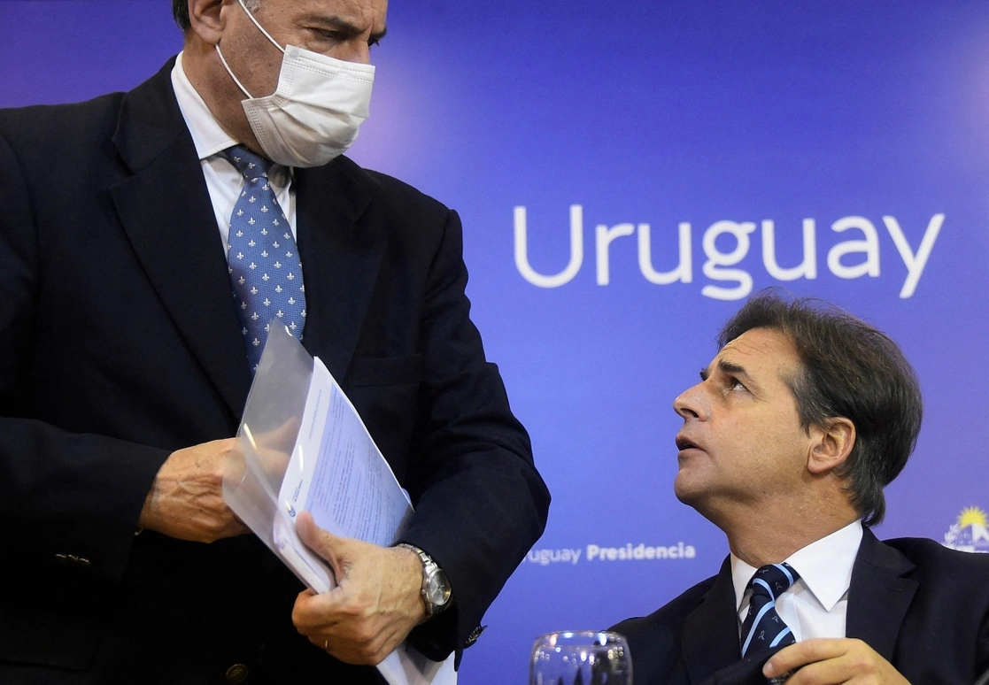 El presidente del país sudamericano, Luis Lacalle Pou (sentado), habla con uno de sus ministros en una conferencia de prensa. Foto Afp