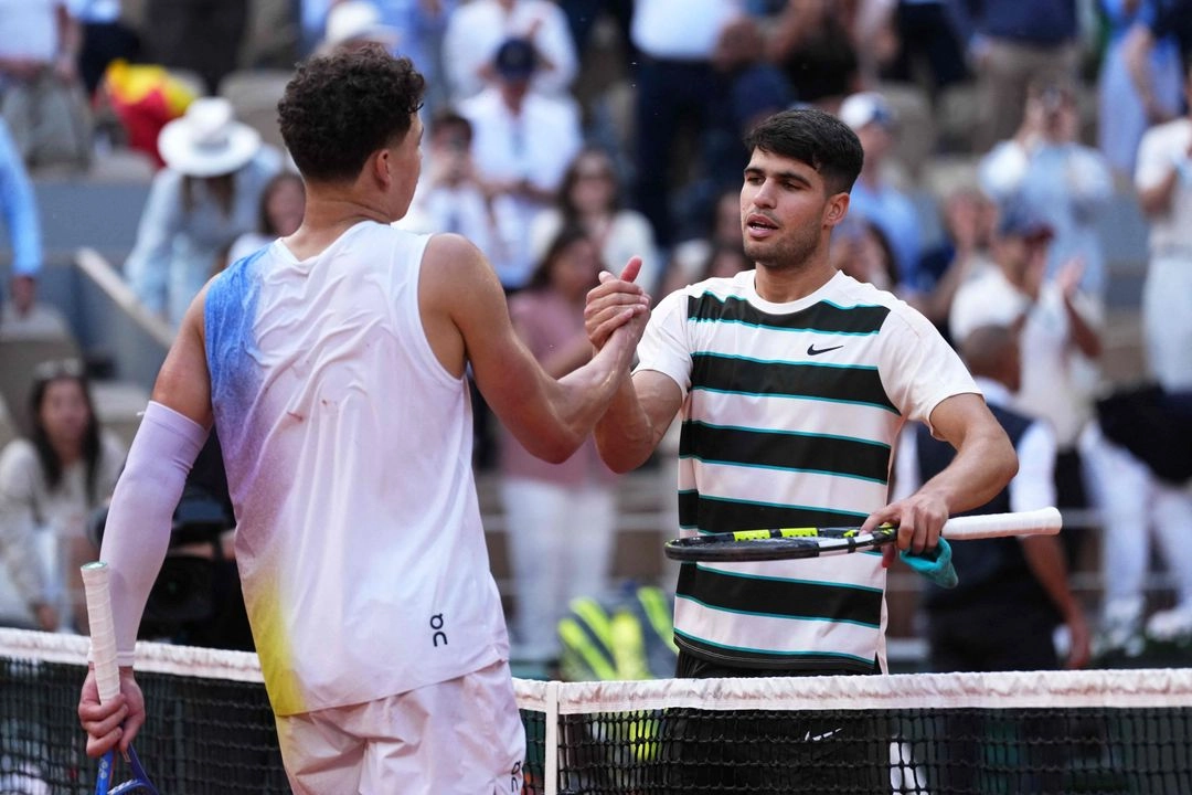El español Carlos Alcaraz (derecha) estrecha la mano del estadunidense Ben Shelton al final de su partido individual masculino en la octava jornada del Abierto de Francia. Foto