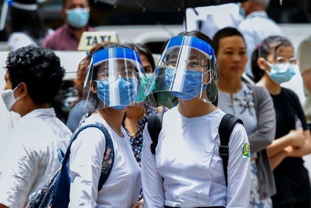 Padres esperan a sus hijos con caretas, durante el primer día de regreso a clases en Rangún, Birmania. Foto Afp 