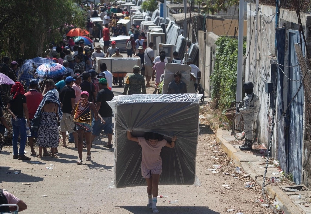 Largas filas realizaron ayer habitantes de La Poza, en el puerto de Acapulco, para recibir los paquetes de enseres domésticos por parte de integrantes de la Sedena y de la Secretaría del Bienestar. Como una medida para evitar acaparamiento o que personas ajenas se beneficien, las autoridades siguen un riguroso censo de los afectados por el huracán 'Otis'. Foto Alfredo Domínguez




