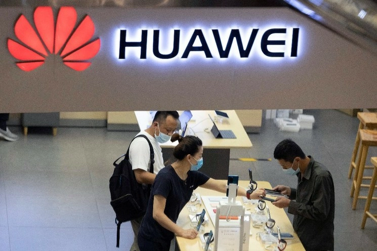 Clientes de una tienda de Huawei en Beijing usan cubrebocas mientras prueban celulares, en imagen de archivo. Foto Ap