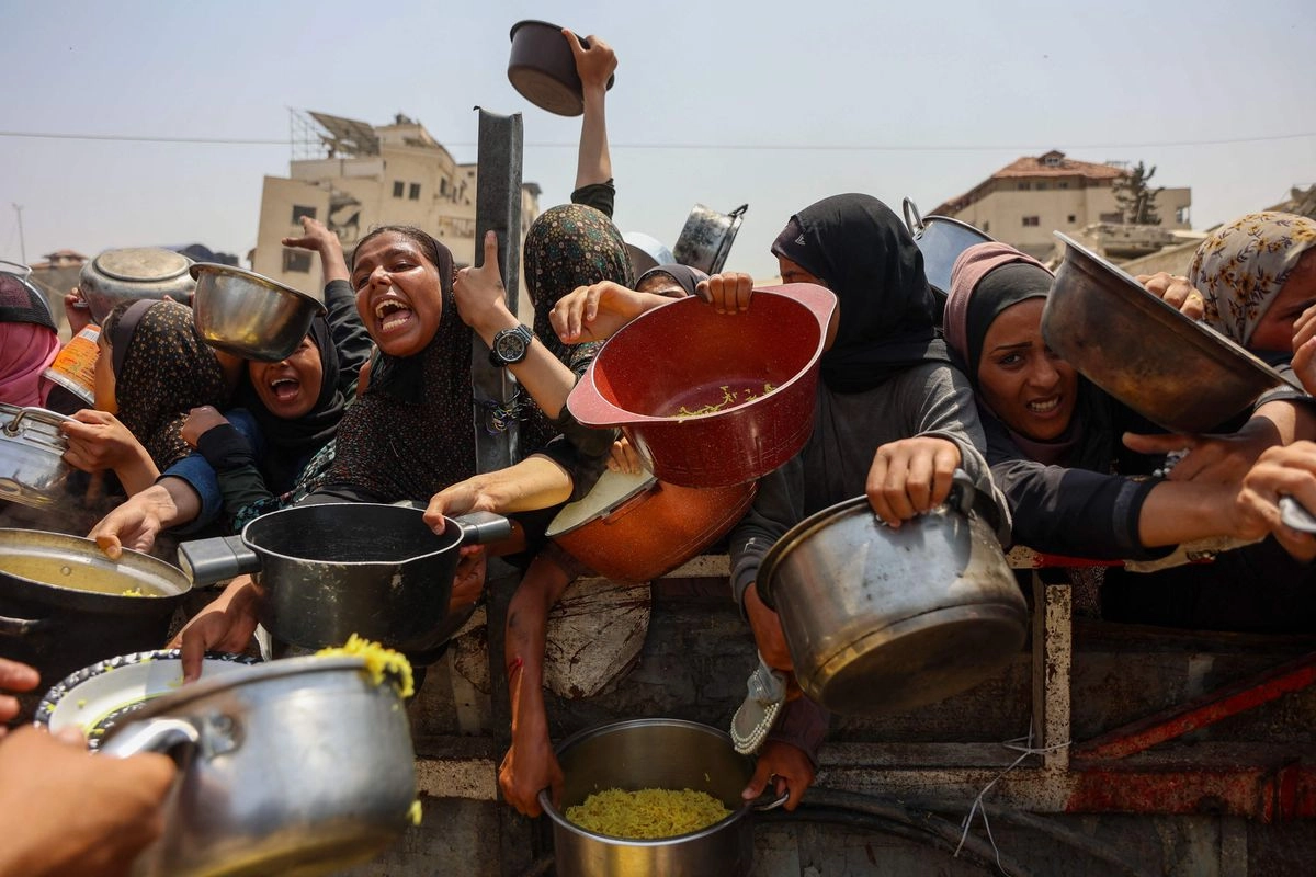 Palestinos se reúnen para recibir comida preparada de un centro de distribución de alimentos en la ciudad de Gaza, el 13 de agosto de 2025. Foto 
