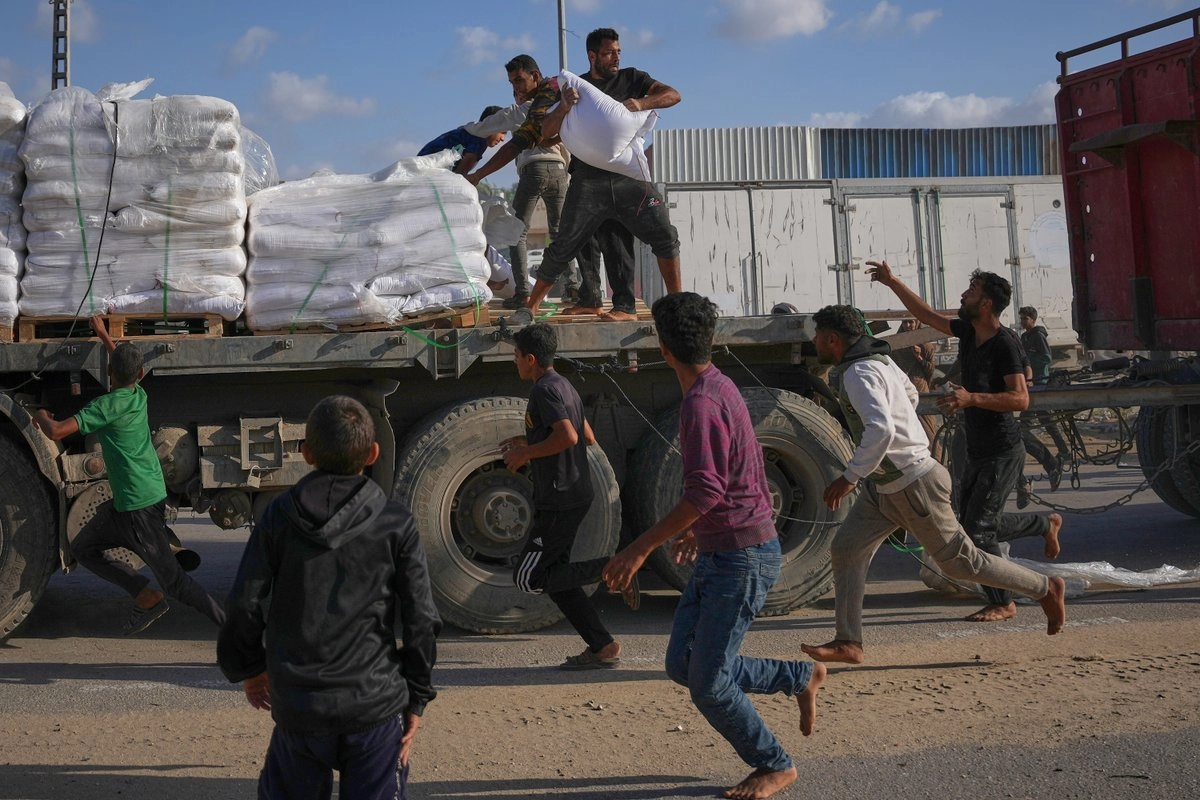 Palestinos se apropian de sacos de harina de un camión en movimiento que transporta ayuda del Programa Mundial de Alimentos (PMA)e, en Deir al-Balah, en el centro de Gaza, el 15 de noviembre de 2025. Foto 