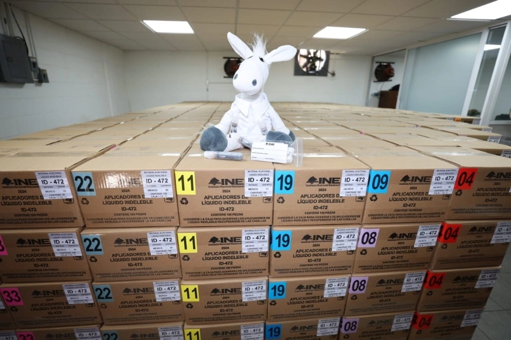 Cajas que contienen los aplicadores de tinta indeleble. Arriba, un muñeco de peluche de una burrita blanca, mascota insignia del Politécnico. Imagen tomada de https://twitter.com/IPN_MX 