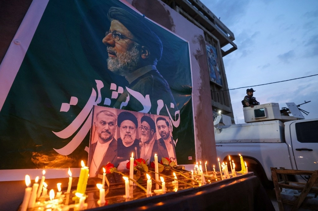 Un soldado iraquí hace guardia junto a una lista de velas junto a personas que presentan sus respetos al difunto presidente de Irán, Ebrahim Raisi, frente a la embajada iraní en Bagdad durante un servicio de condolencias el 20 de mayo de 2024. Foto AFP