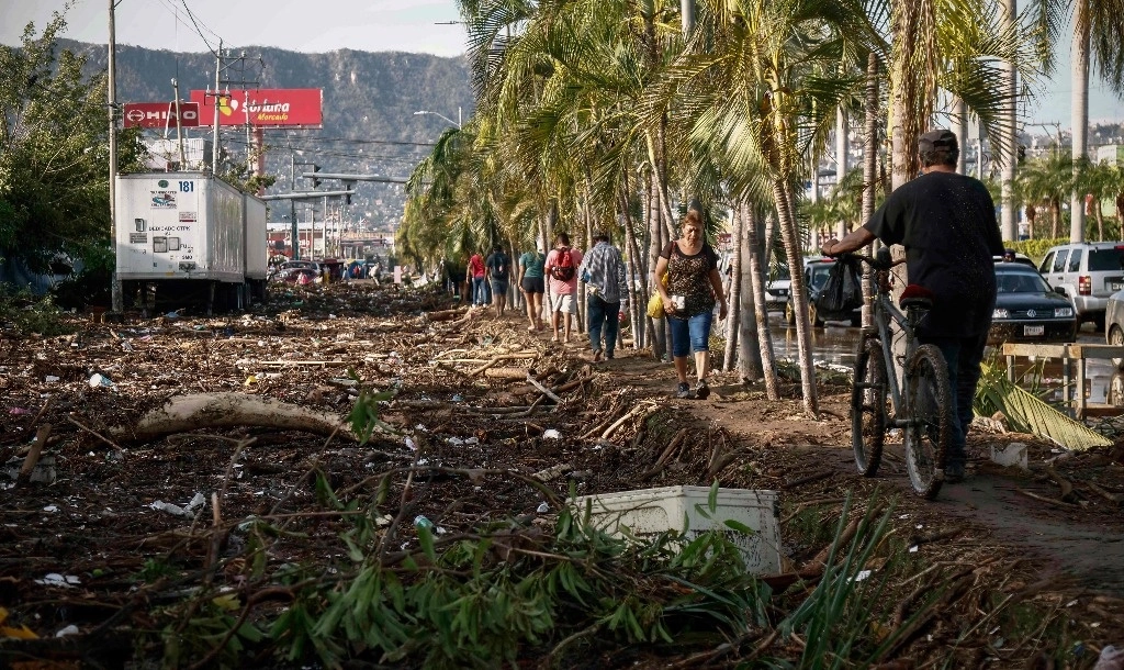 La gente camina junto a los escombros que quedaron después del paso del huracán 'Otis' en Acapulco, Guerrero. Foto AFP 