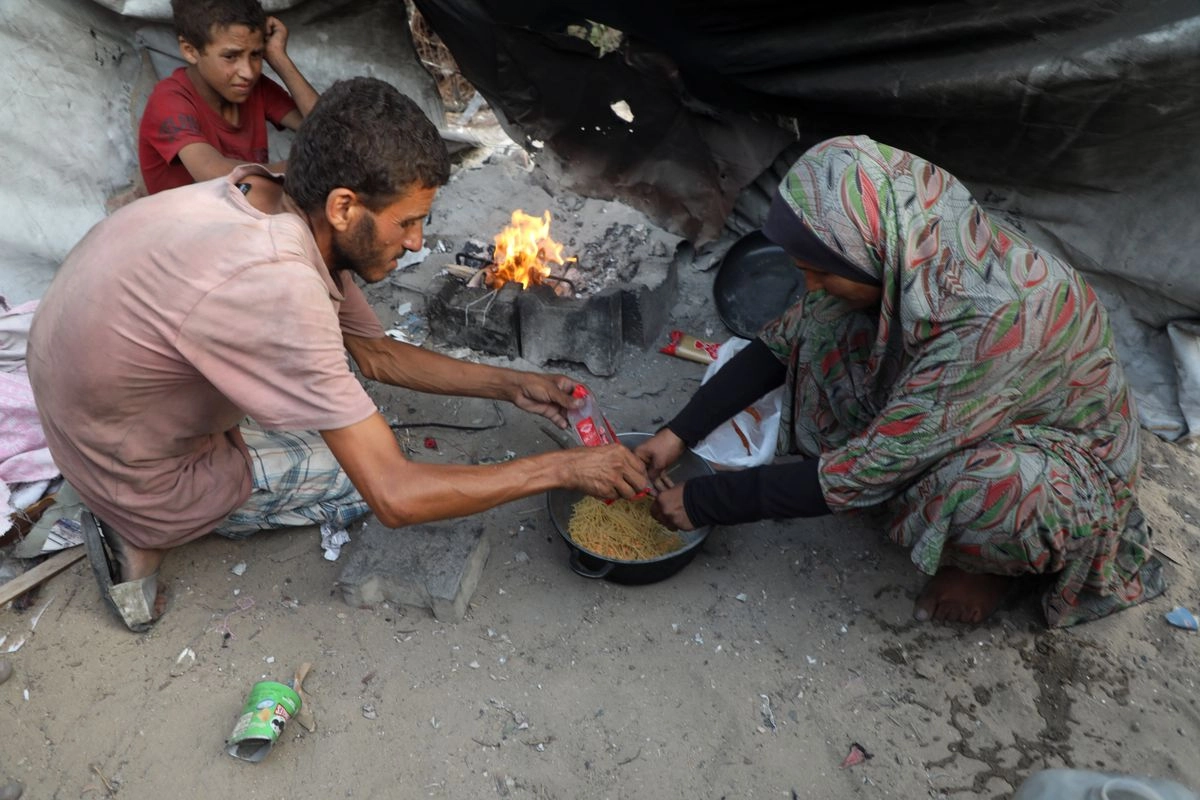 Mohammed Abu Amsha junto a su familia preparan alimentos dentro de su tienda de campaña, en la ciudad de Gaza, el 29 de julio de 2025. Foto
