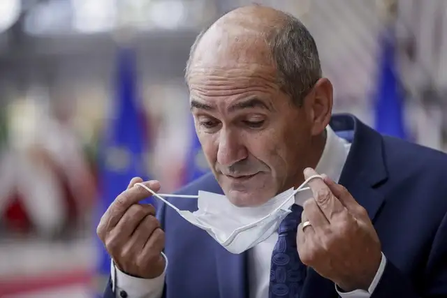 El primer ministro de Eslovenia, Janez Jansa, se quita el cubrebocas a su llegada a una reunión del Consejo Europeo en Bruselas, el jueves pasado. Foto Ap 