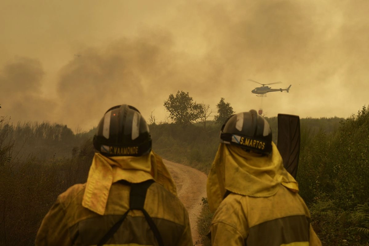 Extinción del fuego en la carretera de acceso a la población de Cualedro, en Galicia, España. 