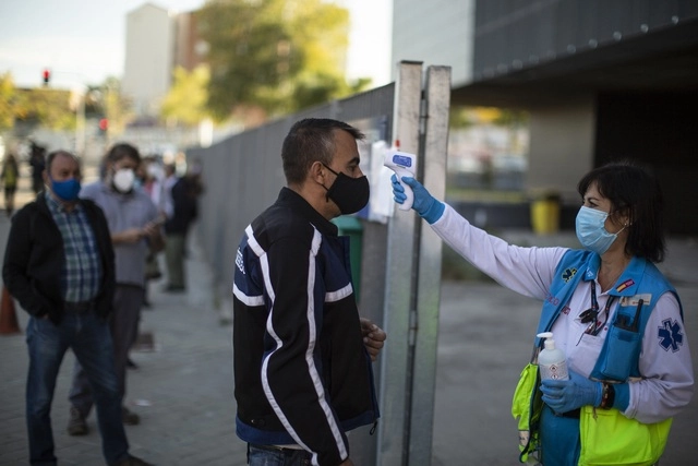 Una empleada de salud revisa la temperatura de un hombre en el barrio de Vallecas, Madrid. Foto Ap 