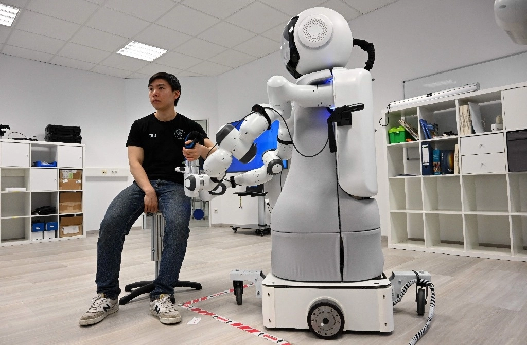Un empleado se sienta frente al robot Garmi en el laboratorio del Centro de Investigación Geriatrónica de la Universidad Técnica de Múnich, en Garmisch-Partenkirchen, sur de Alemania. Foto Afp
