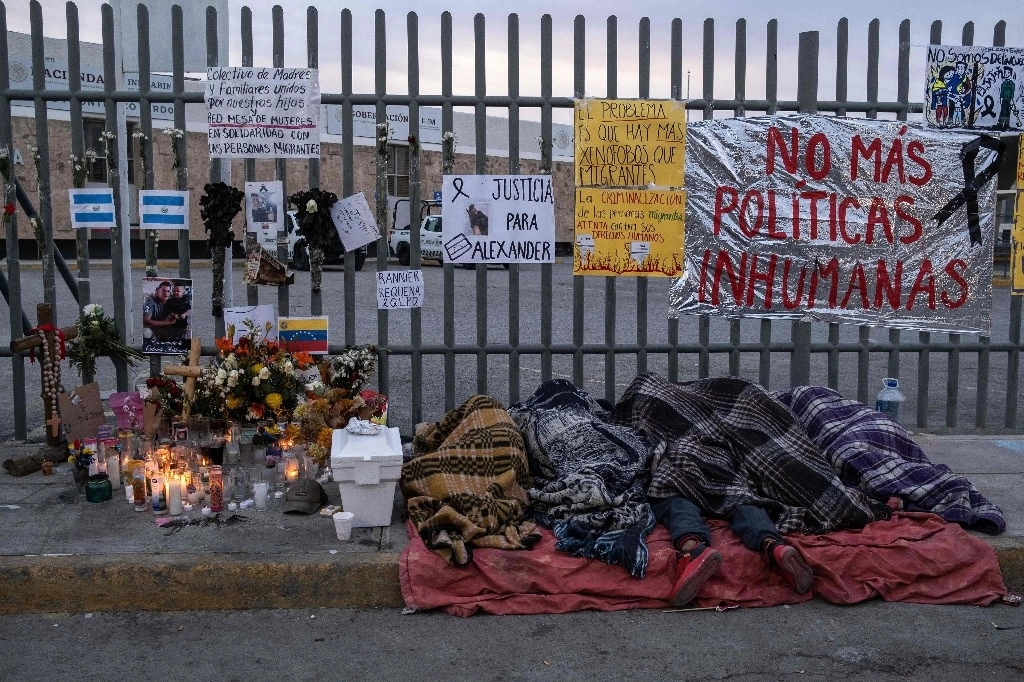 Migrantes duermen frente a la estación del INM que se incendió el 27 de marzo pasado en Ciudad Juárez. Foto Afp
