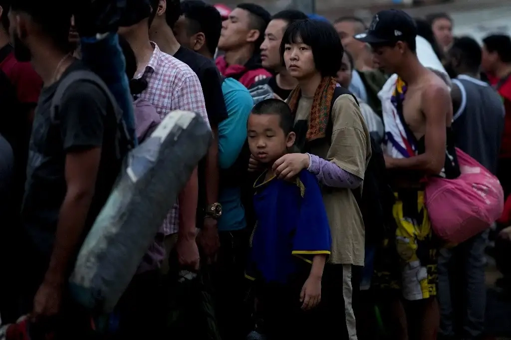 Migrantes chinos se forman para subir a una embarcación. Foto AP / archivo 