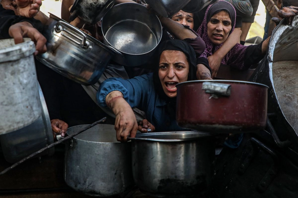 Palestinos desplazados esperando recibir alimentos gratuitos de un centro de distribución de alimentos, en la Ciudad de Gaza. 