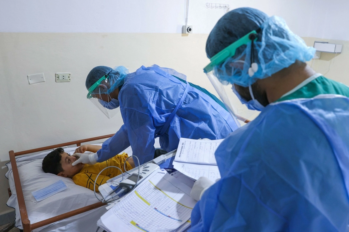 Un médico sirio atiende a un niño en una sala de aislamiento de Covid-19 en un hospital infantil en la ciudad de Idlib, en el noroeste de Siria. Foto Afp