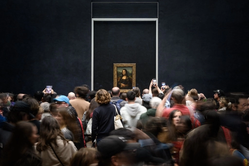 Los visitantes toman una fotografía de la pintura "La Gioconda", La Mona Lisa, del artista italiano Leonardo Da Vinci, en exhibición en una galería del Museo del Louvre en París, el 20 de abril de 2023. Foto Afp 