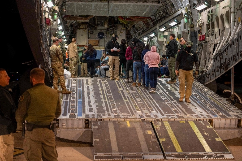 Esta imagen del Departamento de Defensa muestra a aviadores estadunidenses y agentes de Aduanas y Protección Fronteriza, mientras guían a migrantes indocumentados dentro de un C-17 Globemaster III de uso militar en el aeropuerto de Tucson, Arizona. Foto vía Afp