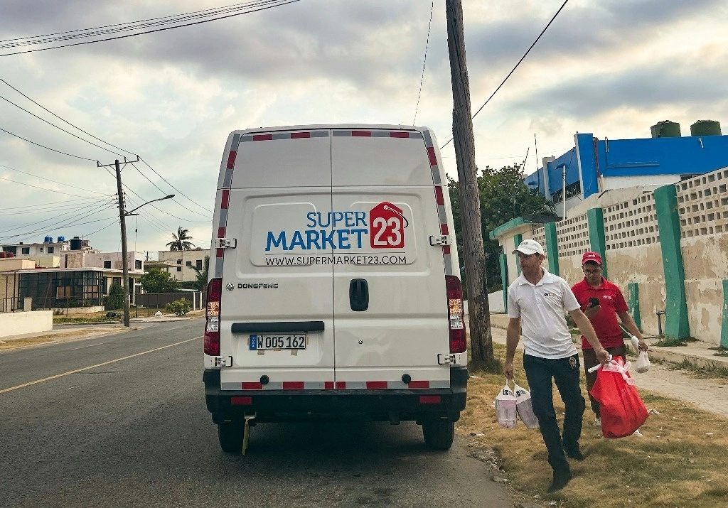 Empleados de una empresa estadunidense de envío de remesas entregan alimentos en una zona de La Habana, el 22 de mayo de 2024. Foto Afp