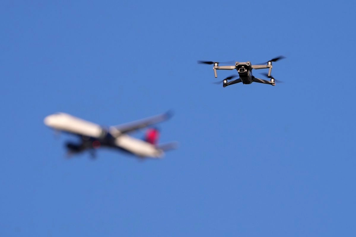 Un dron sobrevuela el espacio aéreo fuera del perímetro de seguridad que rodea el Aeropuerto Internacional St. Louis Lambert mientras un avión de pasajeros se aproxima para aterrizar.