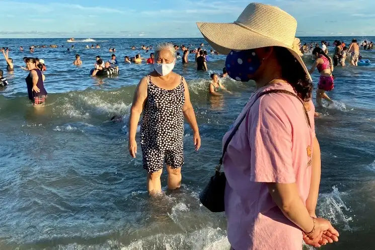 Vacacionistas vietnamitas usan mascarilla en la playa de Vung Tau city, el 26 de julio de 2020, el mismo día que el país reimpuso fuertes restricciones por un rebrote del coronavirus. Foto Ap