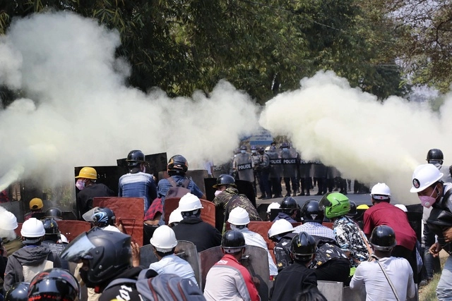 Manifestantes se defienden con extintores del gas lacrimógeno lanzado por la policía, durante una manifestación en Myanmar. Foto Ap 