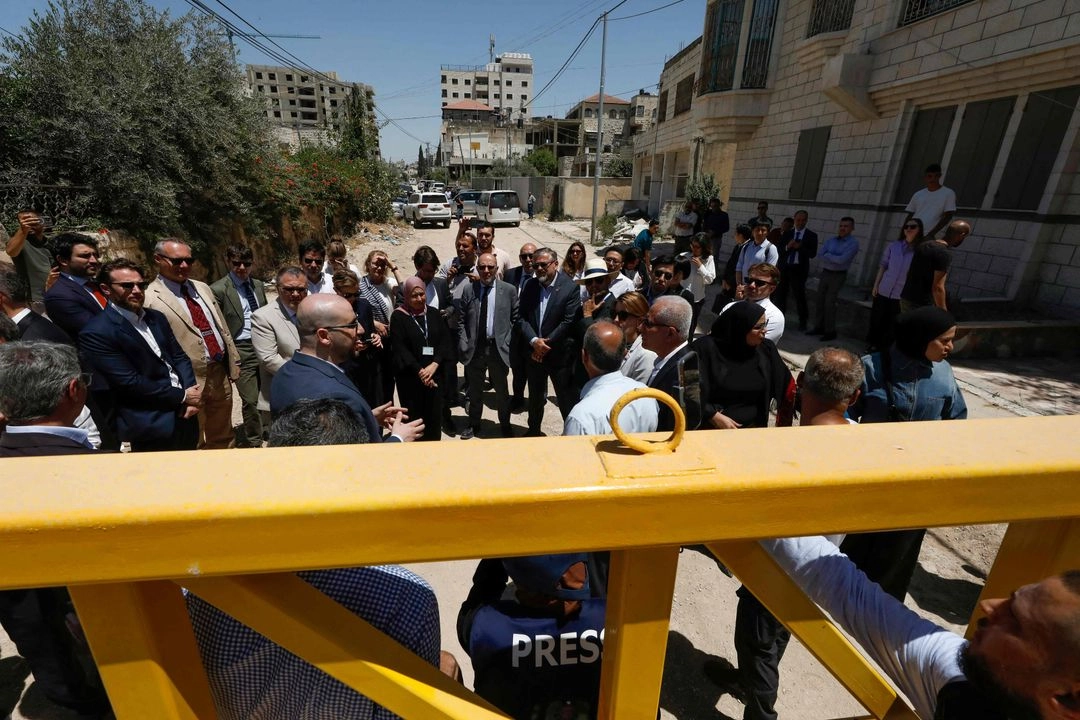 Miembros de una delegación diplomática permanecen tras una puerta en la entrada oriental del campamento de Yenín durante una visita a la ciudad el 21 de mayo de 2025, en medio de una ofensiva militar israelí en curso en la Cisjordania ocupada. La Autoridad Palestina acusó a las fuerzas israelíes de disparar contra diplomáticos durante su visita a la conflictiva ciudad cisjordana de Yenín y difundió un vídeo en el que se ve a dos soldados apuntando con fusiles a un grupo de personas. 
