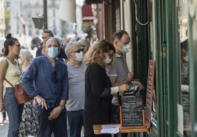 Personas con cubrebocas hacen fila en una heladería en París, Francia. Foto Ap 