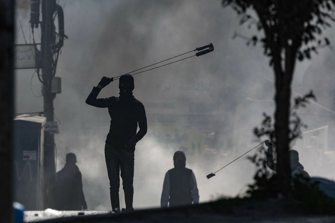 Manifestantes palestinos arrojan piedras a las tropas israelíes durante los enfrentamientos en la ciudad de Al-Ram, en Cisjordania un día después de una incursión israelí mortal en el campamento de Jenin, el 27 de enero de 2023. Foto Afp