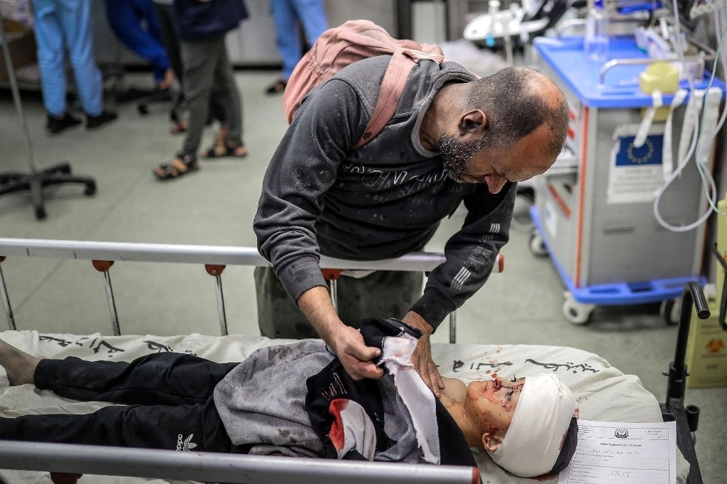 Un palestino herido consuela a un niño herido acostado en una camilla en el hospital tras el bombardeo israelí de Khan Yunis en el sur de la franja de Gaza, el 15 de noviembre de 2023. Foto Afp