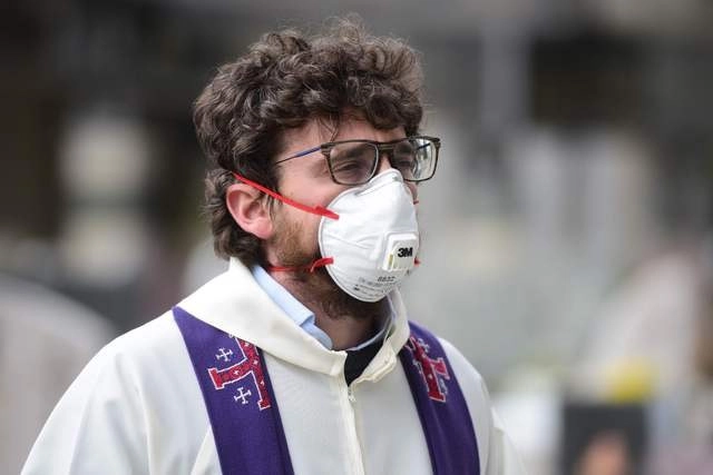 Un sacerdote usa cubrebocas durante un funeral en Italia. Foto Afp