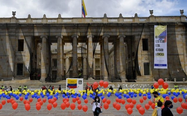Una mujer coloca globos con los colores de la bandera colombiana en la Plaza Bolívar de Bogotá, durante un acto que conmemora el cuarto aniversario del referéndum realizado para ratificar un histórico acuerdo de paz entre el gobierno y la guerrilla de las FARC. Foto Afp