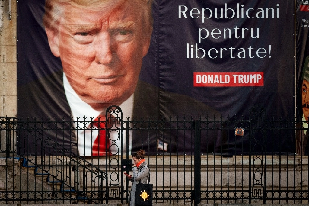 Una mujer mira un teléfono móvil frente a una gran pancarta que dice "Republicanos por la libertad" y que muestra al presidente electo de Estados Unidos, Donald Trump. Foto Ap