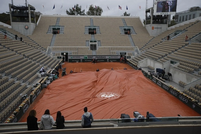 Trabajadores cubren la cancha por la lluvia durante la cuarta ronda del Abierto de Francia. Foto Ap