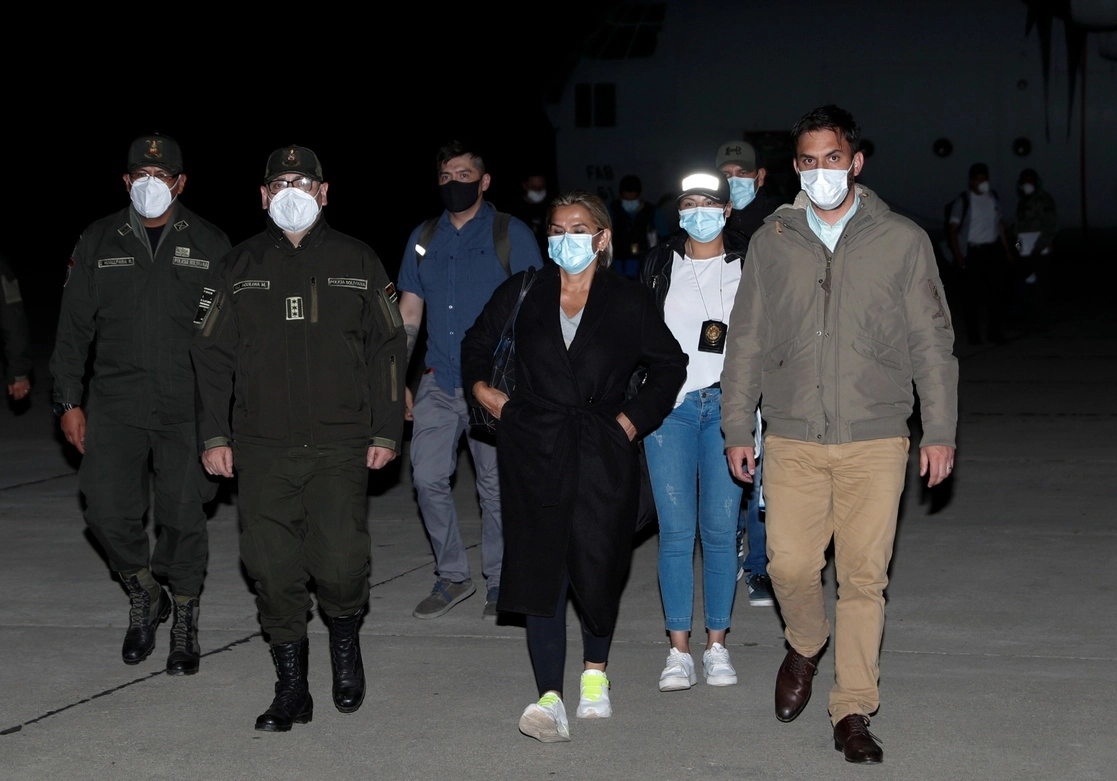 Jeanine Áñez (centro), quien encabezó el gobierno 'de facto' de Bolivia en 2019, es custodiada por el ministro de Gobierno Carlos Eduardo del Castillo (der) y el comandante de la policía, Jhonny Aguilera, en el aeropuerto militar de El Alto, Bolivia, el sábado 13 de marzo de 2021. Foto Ap