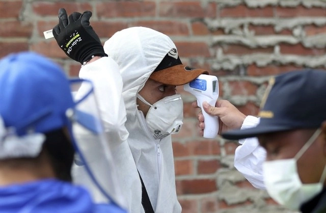 Un trabajador del mercado de Corabastos, uno de los centros de distribución de comida más grandes de América Latina, toma la temperatura de un hombre en Bogotá, Colombia. Foto Ap 