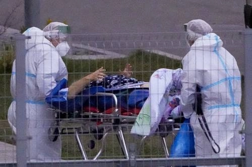 Una persona sospechosa de estar infectada con Covid-19 es ingresada por trabajadores sanitarios en el hospital Kommunarka de Moscú. Foto Ap