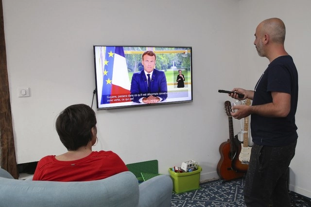 Una familia escucha el discurso televisado que dio el presidente Emmanuel Macron sobre el Covid-19, economía y manifestaciones antirracistas. Foto Ap 