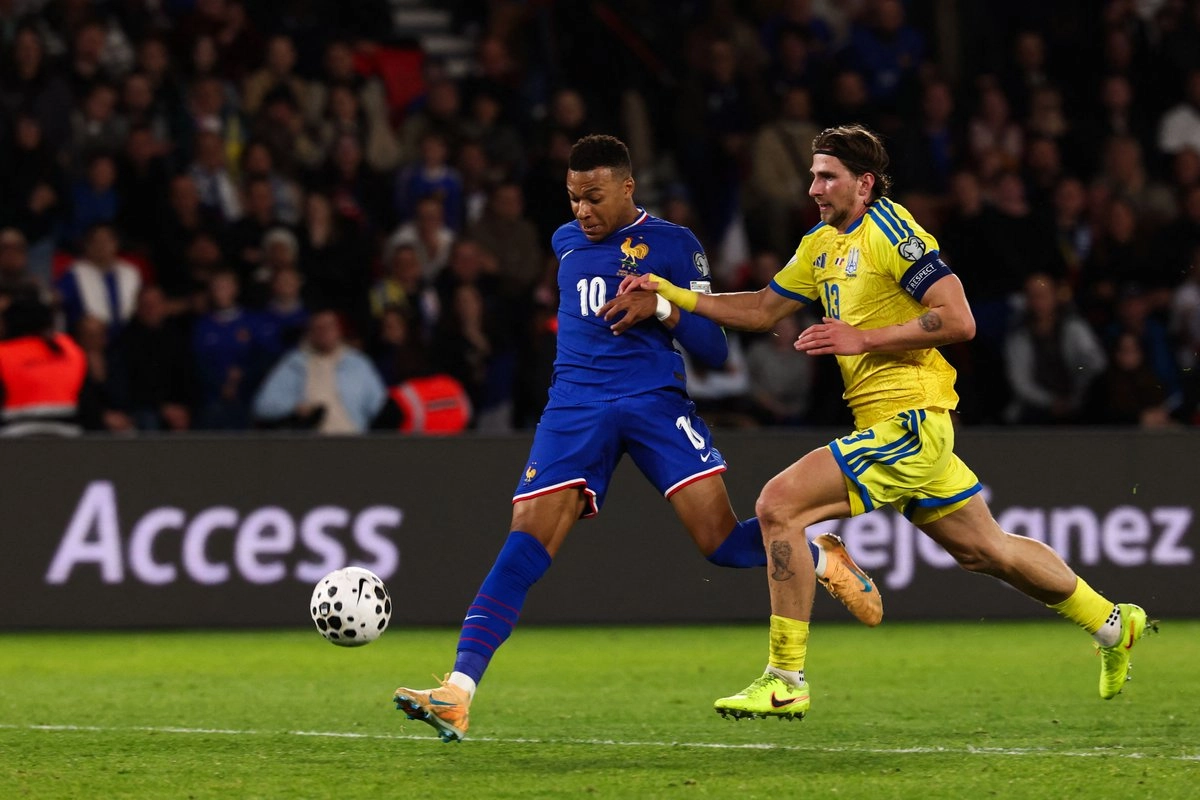 El delantero francés Kylian Mbappé (izq.), número 10, disputa el balón con el defensor ucraniano Illia Zabarnyi, número 13, durante el partido de clasificación para la Copa Mundial de la FIFA 2026. Foto