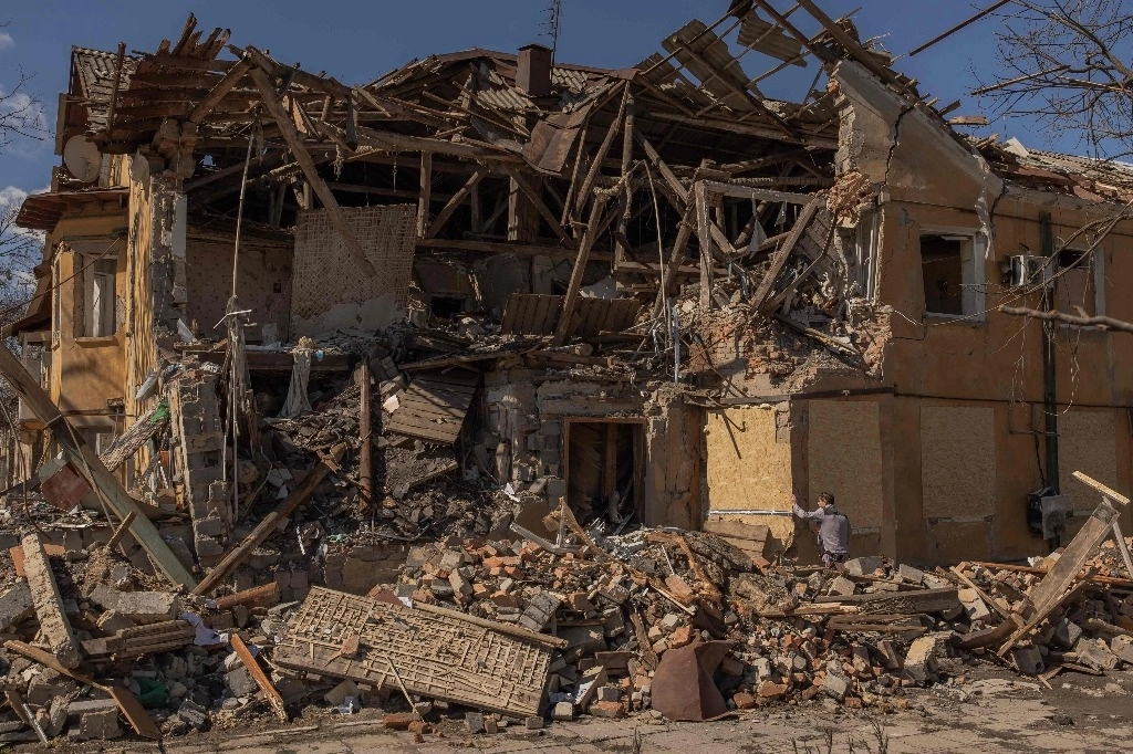 Un hombre cubre las ventanas con tablas de madera contrachapada de un edificio que resultó gravemente dañado tras un reciente bombardeo, en la ciudad de Mykolaivka, cerca de Sloviansk, en el norte de la región de Donetsk, al este de Ucrania, el 30 de marzo de 2024. Foto Afp