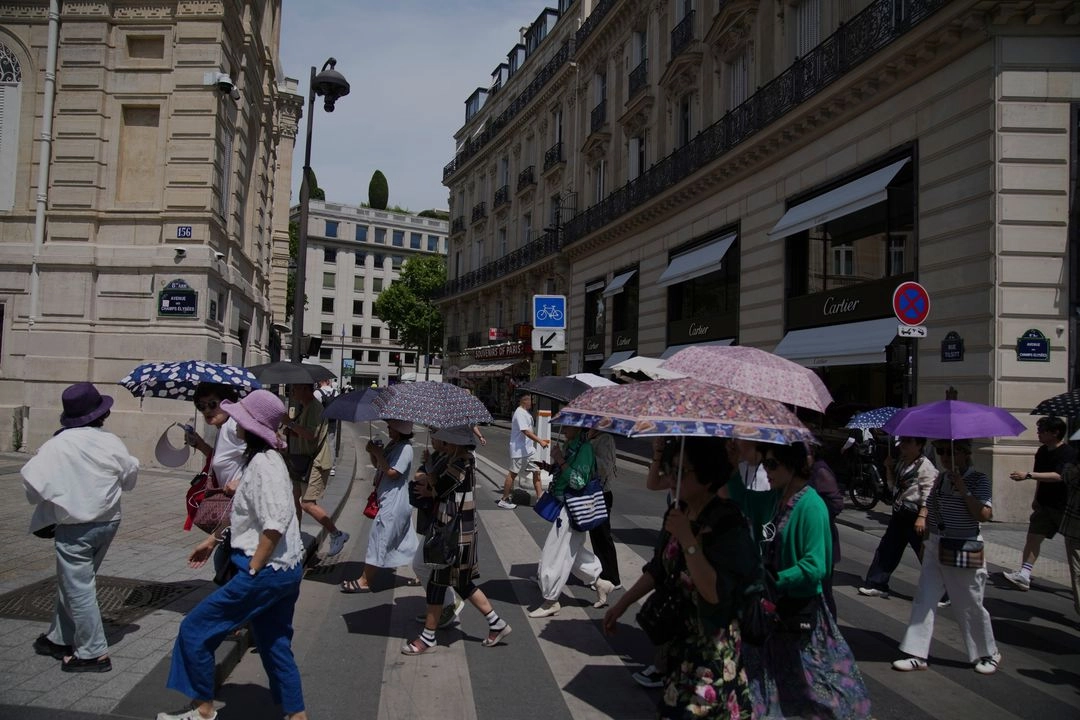 Los turistas usan paraguas para protegerse del sol mientras la temperatura subió a 31 grados Celsius (88 grados Fahrenheit) en París, el 20 de junio de 2025.
