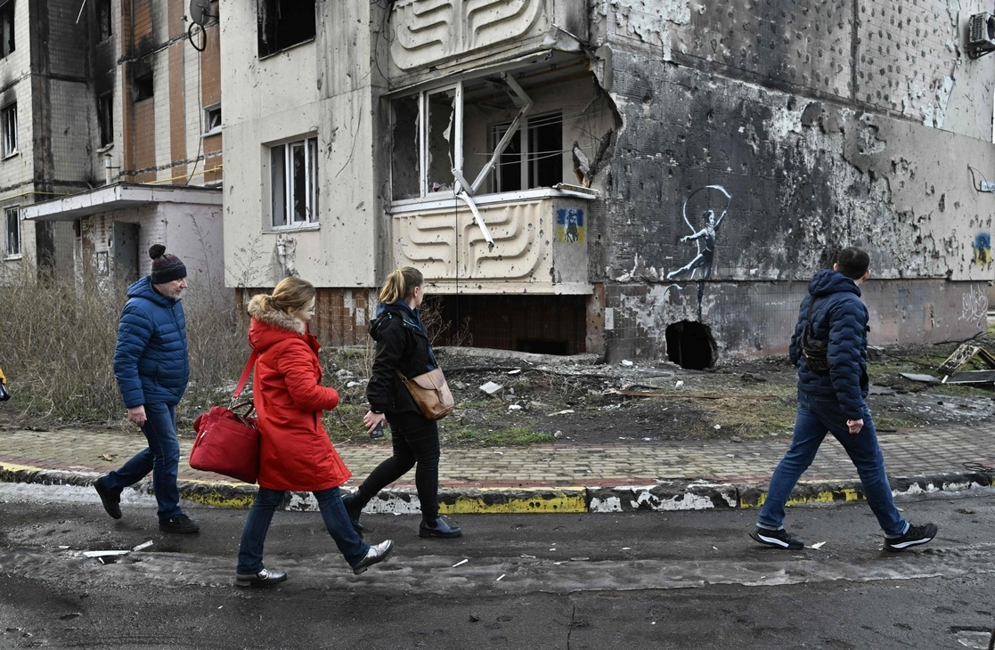 La gente pasa junto a un graffiti de Banksy en una pared de un edificio residencial gravemente dañado en Irpin, al noroeste de Kiev. Foto Afp / Archivo