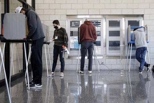 Un voluntario de la Universidad de Iowa desinfecta las cabinas de votación en el Centro de Bienestar y Recreación del campus. Foto Ap