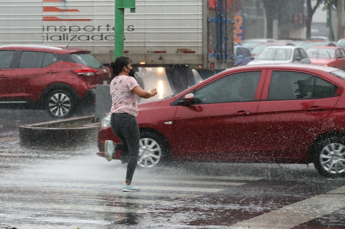 Una mujer corre para esconderse de la lluvia. Foto Roberto García/ Archivo