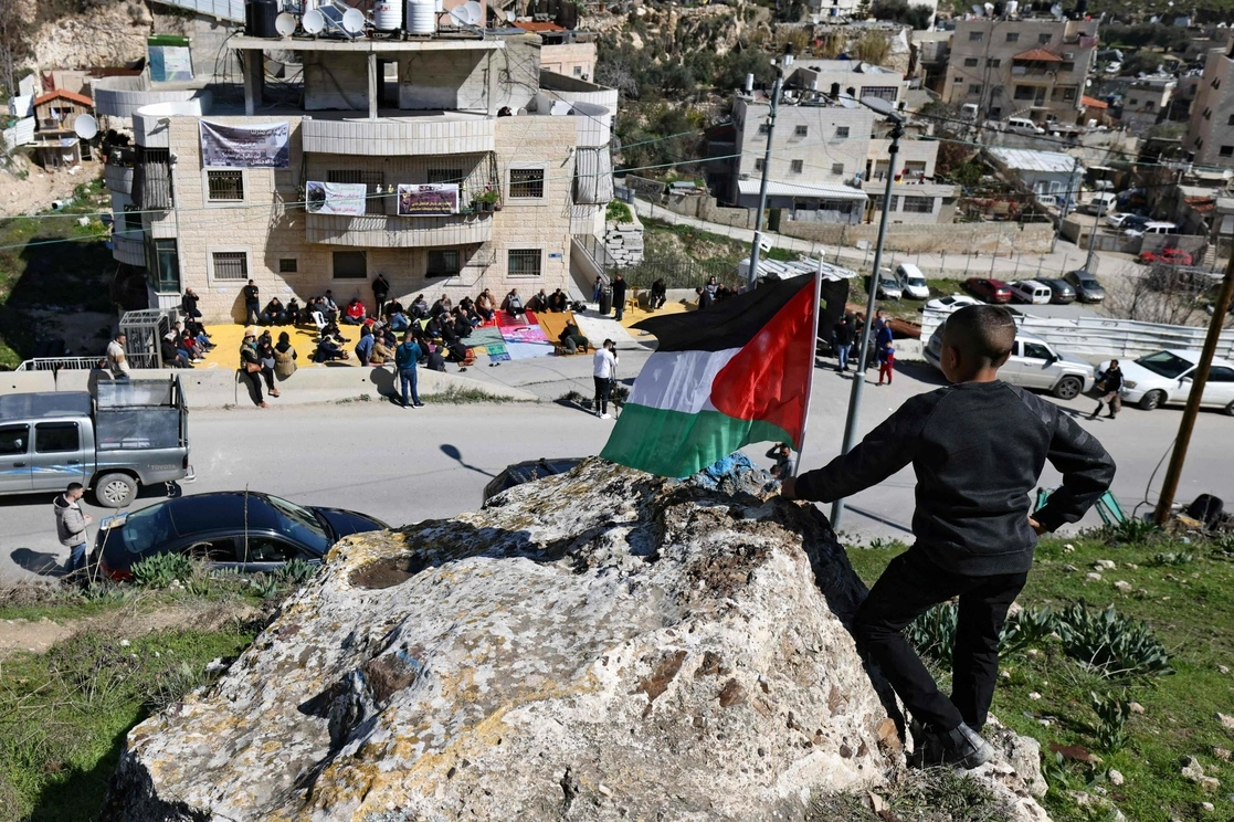 Un niño ondea una bandera nacional palestina mientras la gente realiza la oración del viernes en el barrio árabe de Silwan en el este de Jerusalén. Foto Afp